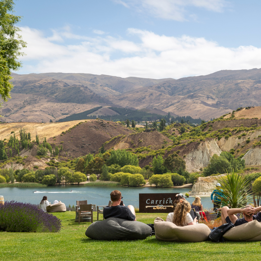 guests seated on bean bags outdoors at carrick winery in central otago with the mountains in the background in spring